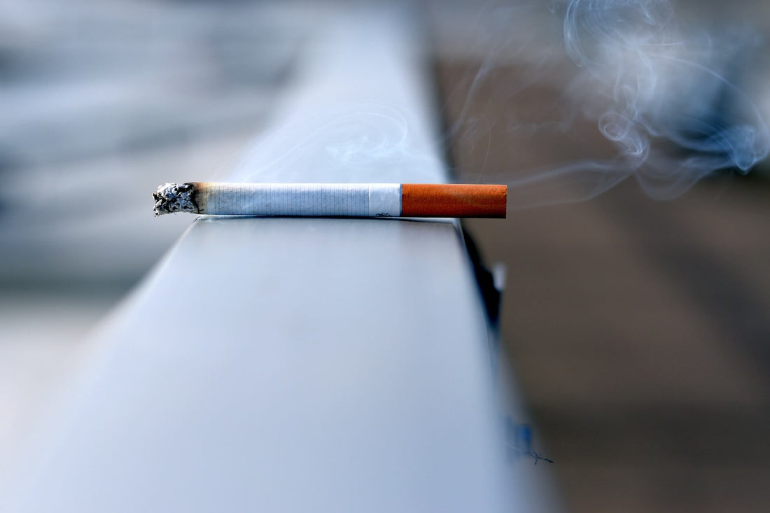A lit cigarette sitting on a railing