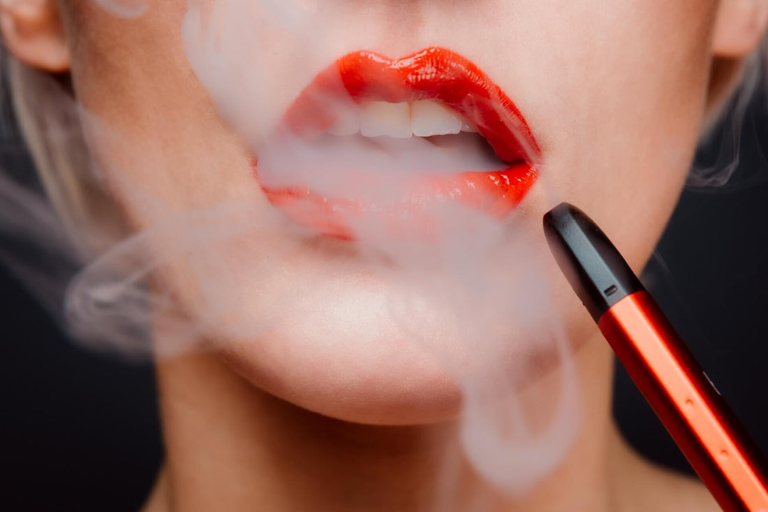 Woman wearing red lipstick exhales vape smoke